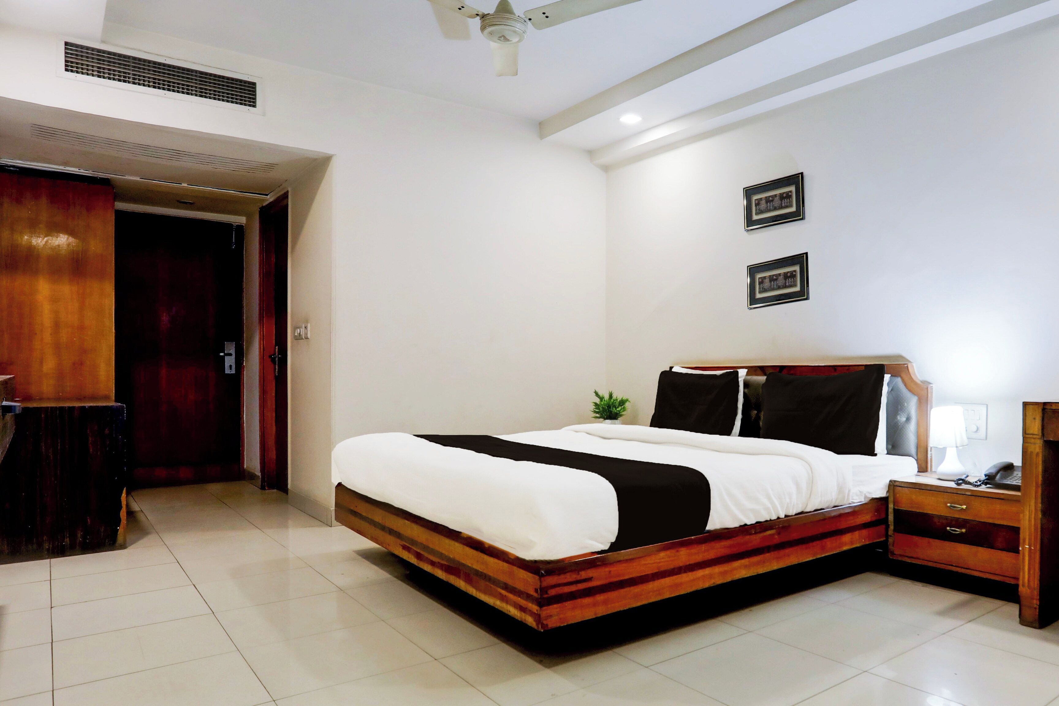 Un dormitorio con cama, mesita de noche, lámpara y ventilador de techo.