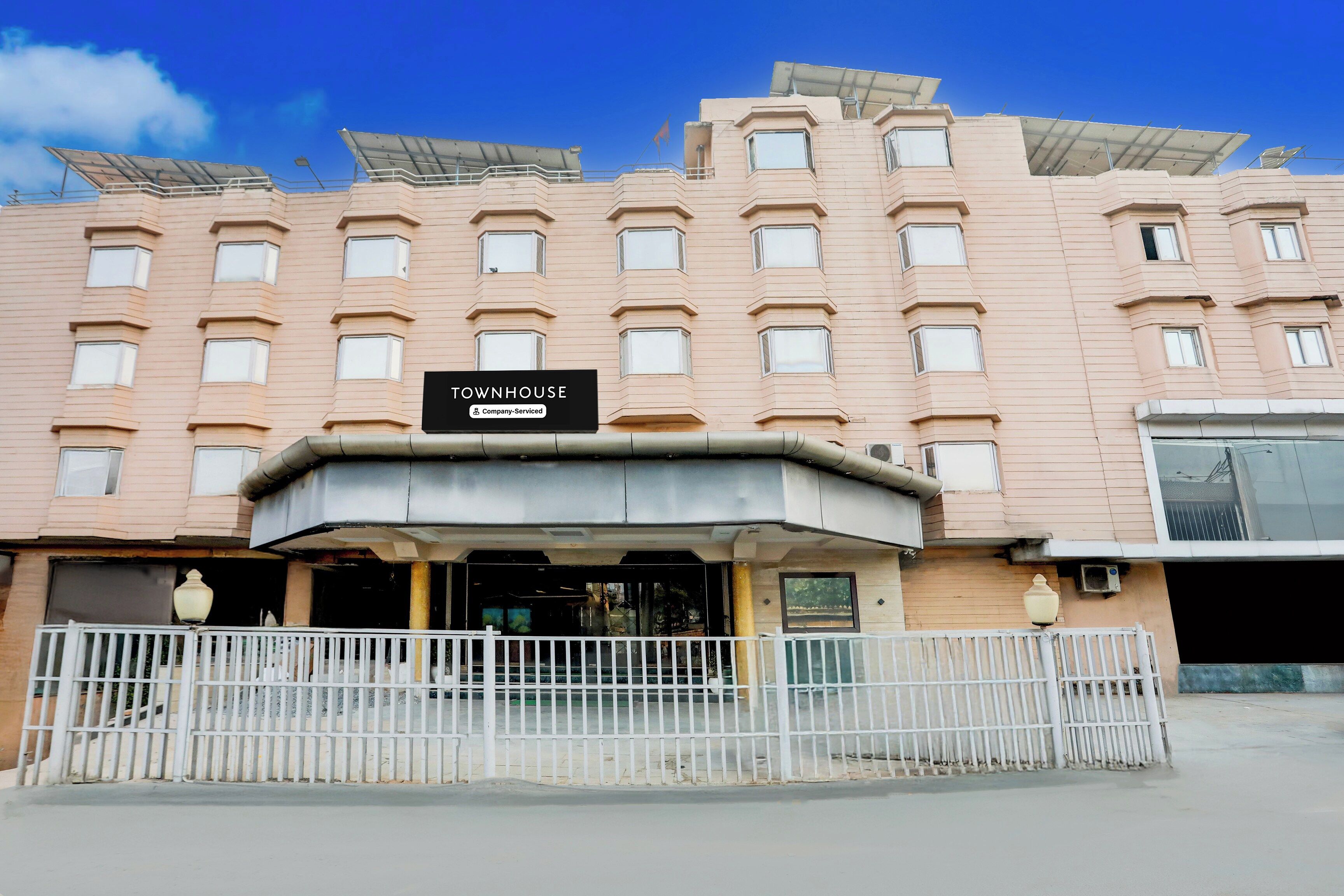 A multi-story building with a sign reading 'TOWNHOUSE' and a company-serviced symbol.