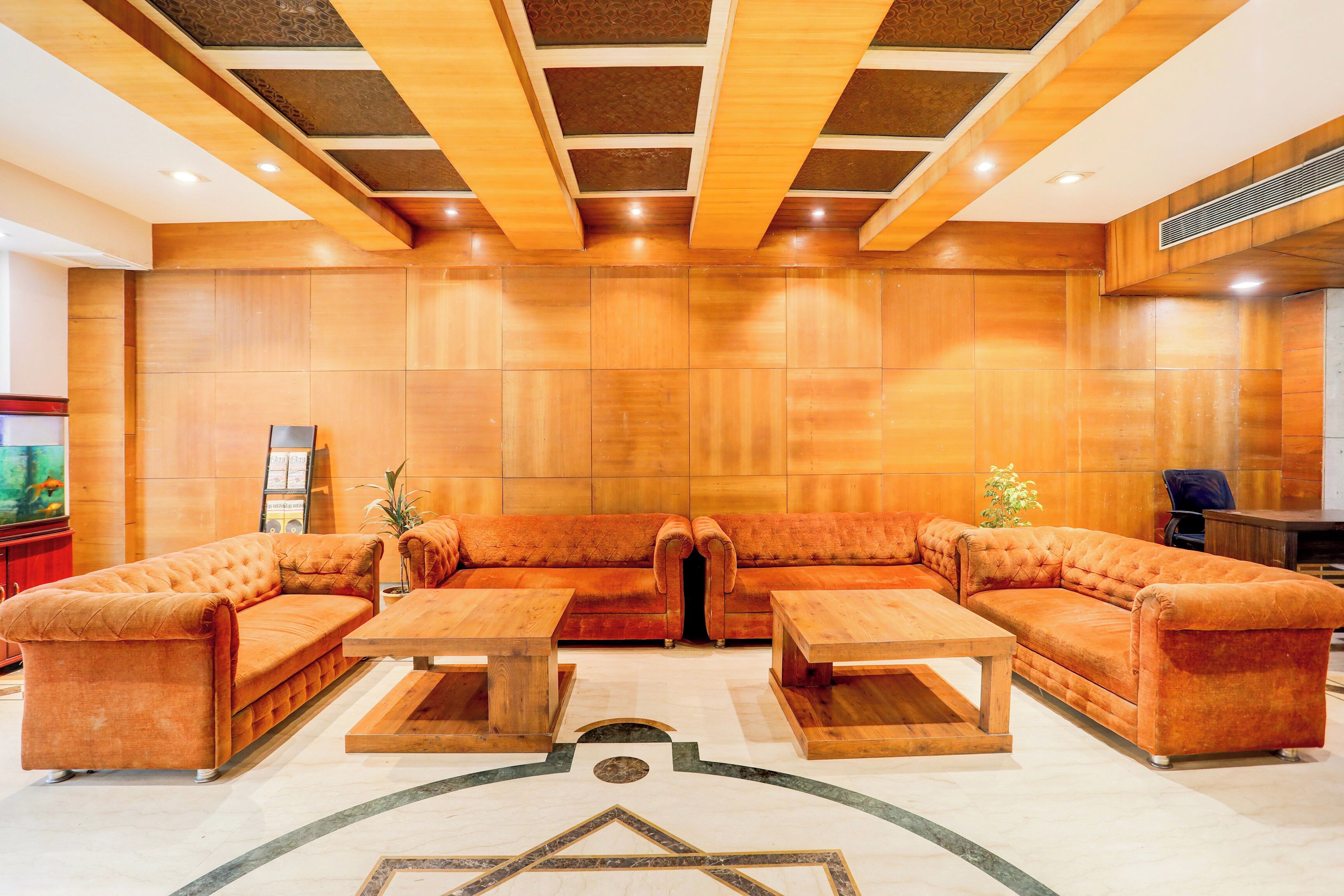 A spacious lobby with a large sectional sofa, two wooden coffee tables, and a decorative floor pattern.