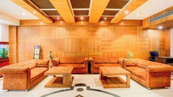 A spacious lobby with a large sectional sofa, two wooden coffee tables, and a decorative floor pattern.