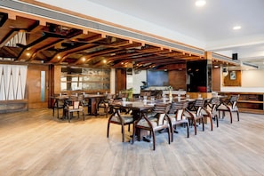 Un restaurante espacioso con vigas de madera y un techo alto. Mesas y sillas dispuestas para comer.