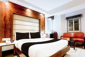 Una habitación de hotel con una cama grande, mesitas de noche, un escritorio y dos sillas.