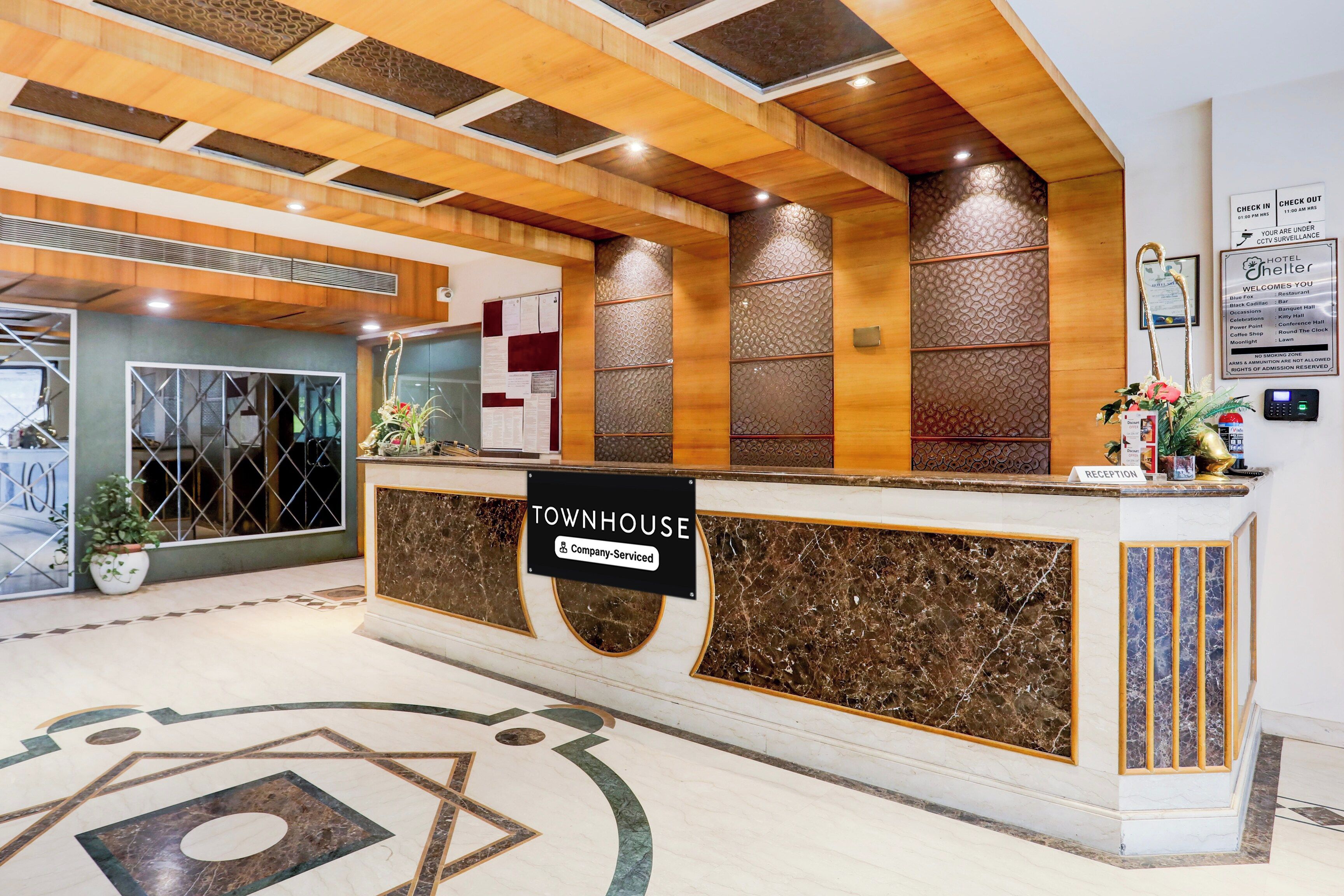 Zona de recepción de hotel con mostrador de mármol, un cartel que indica servicio de empresa y un mostrador de recepción.