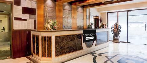 A reception desk with a sign reading 'TOWNHOUSE Company Serviced' and a statue of a deity.