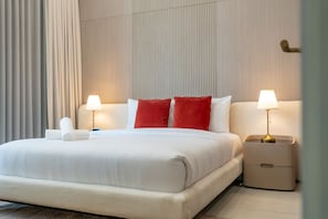 A hotel room with a bed, two bedside lamps, a nightstand, and a towel. - Peaceful 1BR with Serene Community Views, Just Steps from the Park (Dubai)