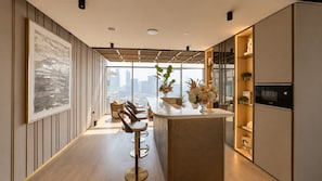 A modern kitchen with a bar area, large windows, and a city view. - Peaceful 1BR with Serene Community Views, Just Steps from the Park (Dubai)