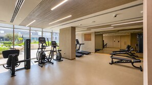 A modern gym with various exercise equipment, large windows, and a clean, spacious layout. - Peaceful 1BR with Serene Community Views, Just Steps from the Park (Dubai)