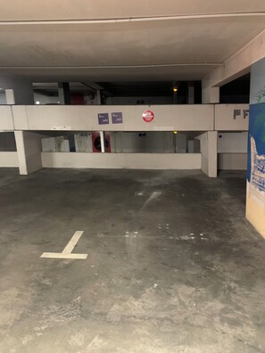 En parkeringskælder med betonstolper, gulve med pile der viser vej, og et ikke-tilladt-adgang-skilt over indgangen.
