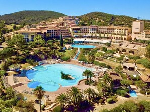 A resort with multiple swimming pools, a central courtyard, and Mediterranean-style architecture.