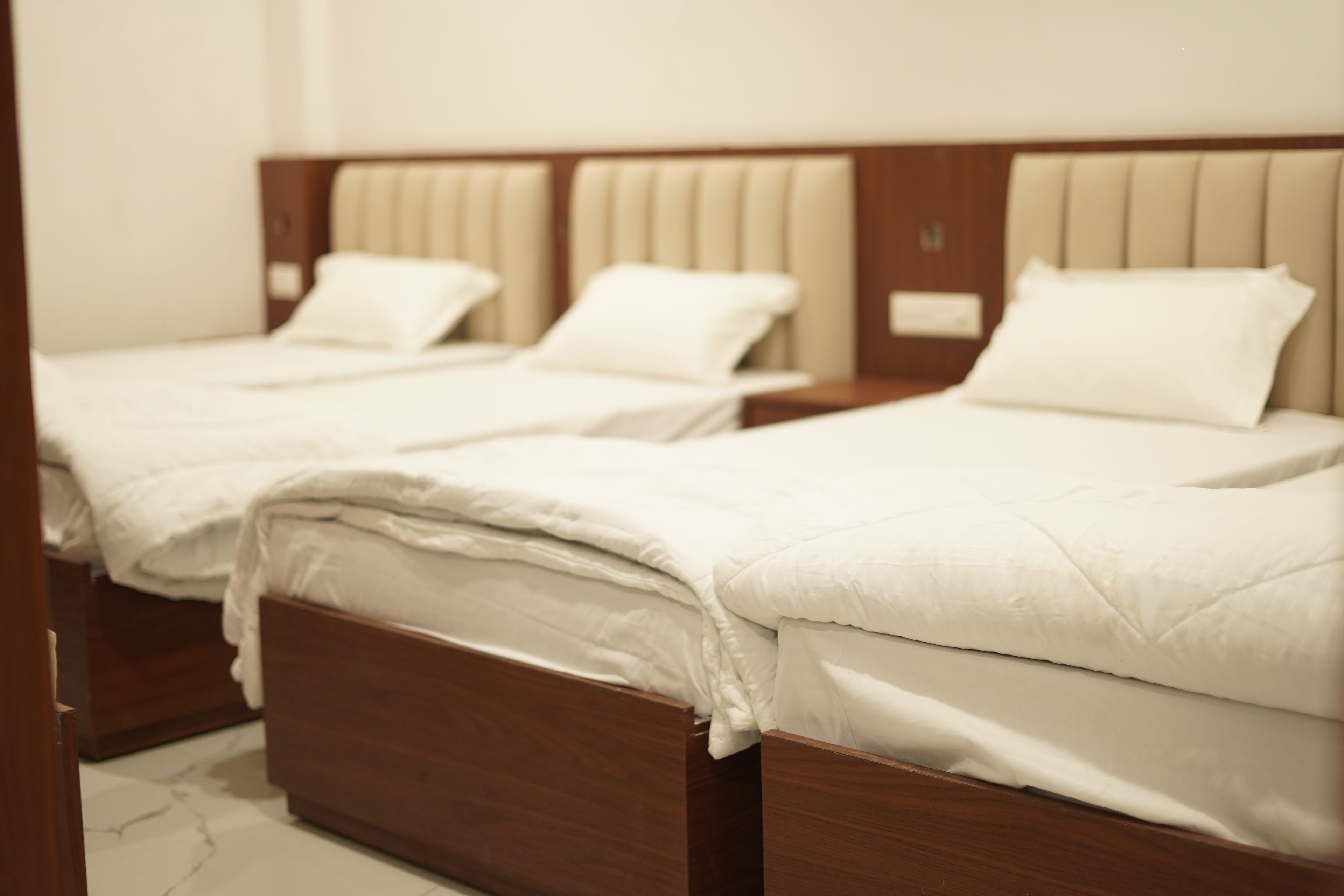 A hotel room with two beds, each with a wooden headboard and white bedding.