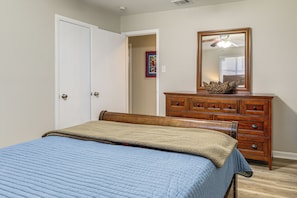 Une chambre à coucher avec un lit, une commode, un miroir et une porte.