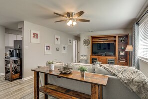 A living room with a ceiling fan, a dining table with chairs, a sofa, and a TV cabinet. - Tiger Town Retreat: Spacious 2-unit Combo! (Baton Rouge)