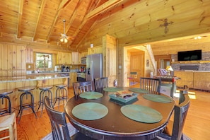 A wooden cabin interior with a kitchen, dining area, and a fireplace. - Hot Tub, Fire Pit, Views & More: Blowing Rock Gem (Blowing Rock)