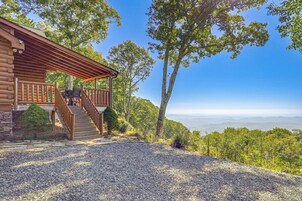 Una cabaña de troncos con porche y vistas a la montaña.