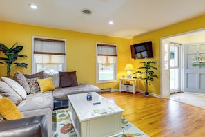 A living room with a sofa, a coffee table, a lamp, and a TV. - 1 Mi to Colonial Beach! Coastal Escape w/ Fire Pit (Colonial Beach)