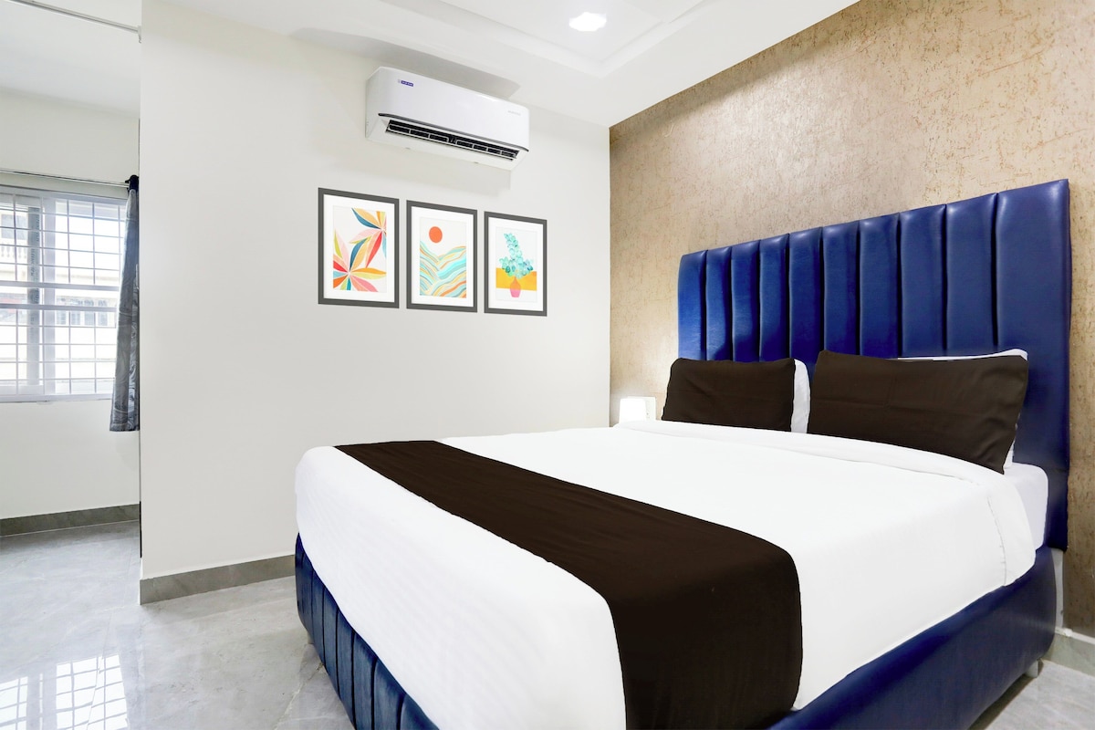 Habitación de hotel con una cama grande, un aire acondicionado de pared y tres obras de arte enmarcadas.