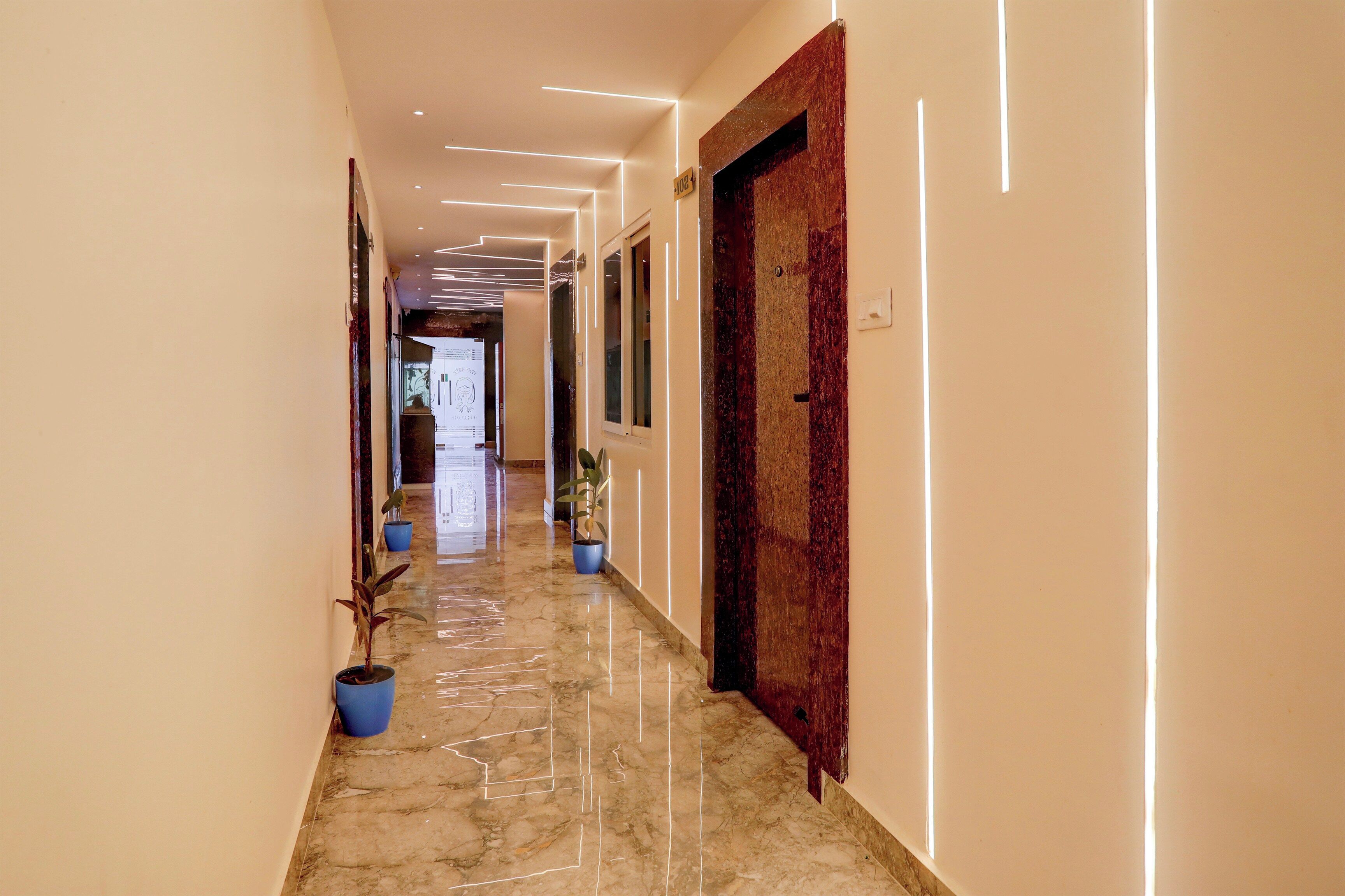 A hallway with a marble floor, potted plants, and a door with a textured surface.
