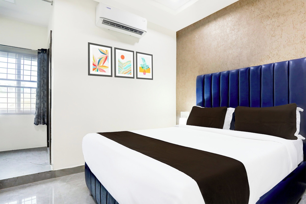 Una habitación de hotel con cama, ventana con cortinas y tres cuadros en la pared.