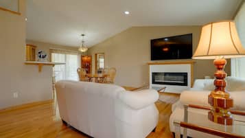 A living room with a sofa, a coffee table, a TV, and a fireplace.