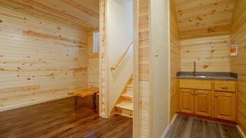 A wooden interior with a staircase leading to a kitchen area.