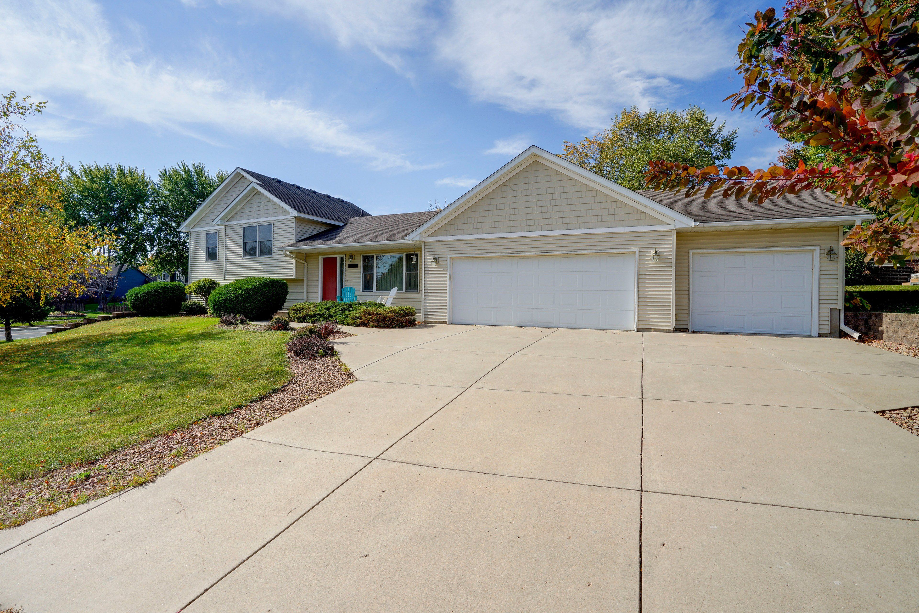 A two-story residential house with a front garage, a covered porch, and a well-maintained lawn.