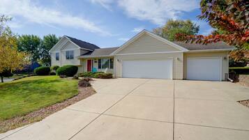 A two-story residential house with a front garage, a covered porch, and a well-maintained lawn.