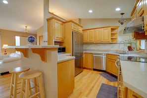 A modern kitchen with wooden cabinets, stainless steel appliances, and a bar area. - Northfield Home Near Nerstrand Big Woods (Northfield)