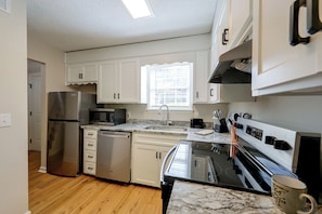 A kitchen with white cabinets, stainless steel appliances, a microwave, and a window with blinds. - 6 Mi to the Masters: North Augusta Condo (North Augusta)