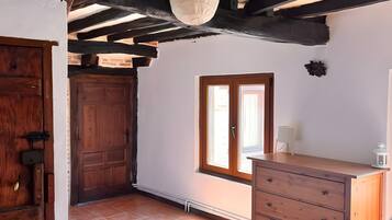 Een kamer met een houten kast, een deur, een raam en een betegelde vloer.