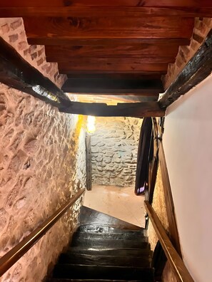 A narrow stone staircase with wooden railings leading to a lower level.