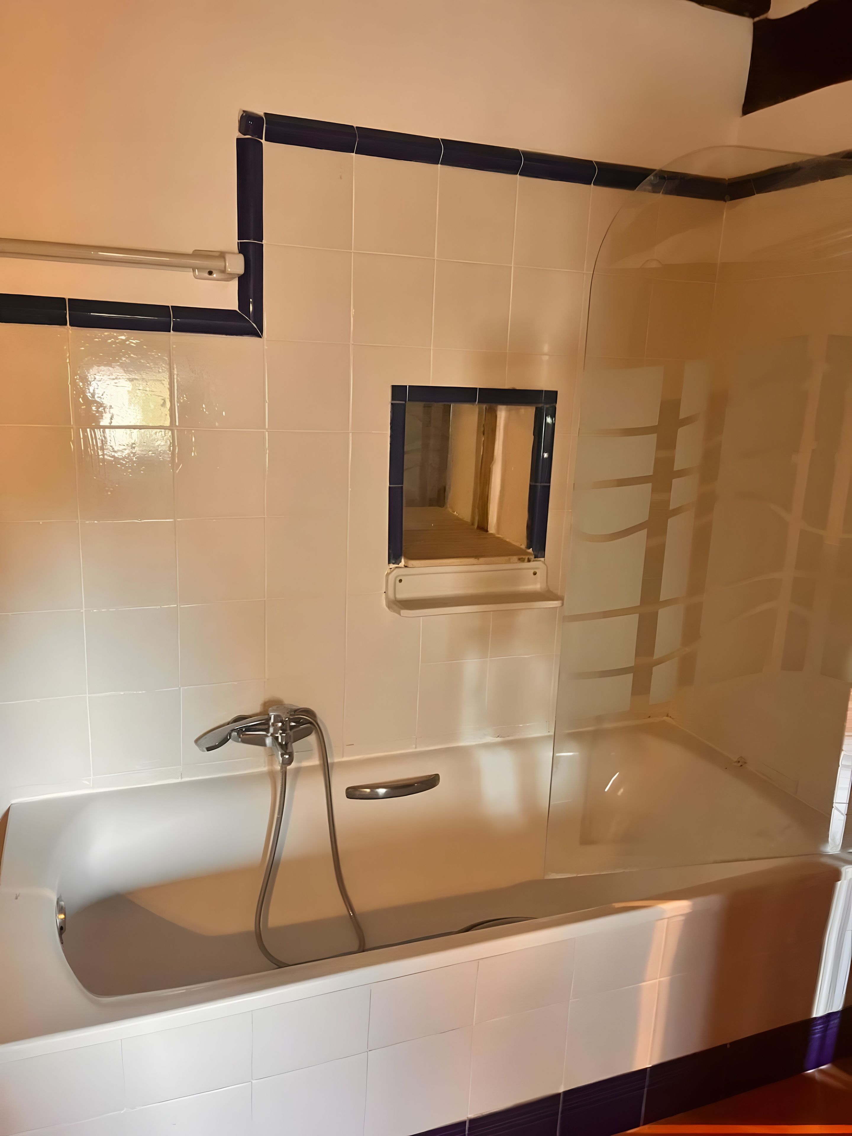 A bathroom with a bathtub, a shower, and a mirror.