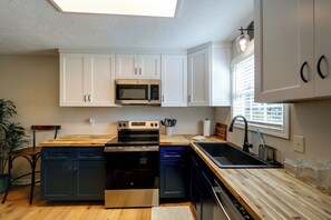 Una cocina moderna con armarios blancos, un microondas, un horno, un lavavajillas y un lavabo.