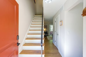 Una escalera de madera con barandilla negra que lleva a una puerta.