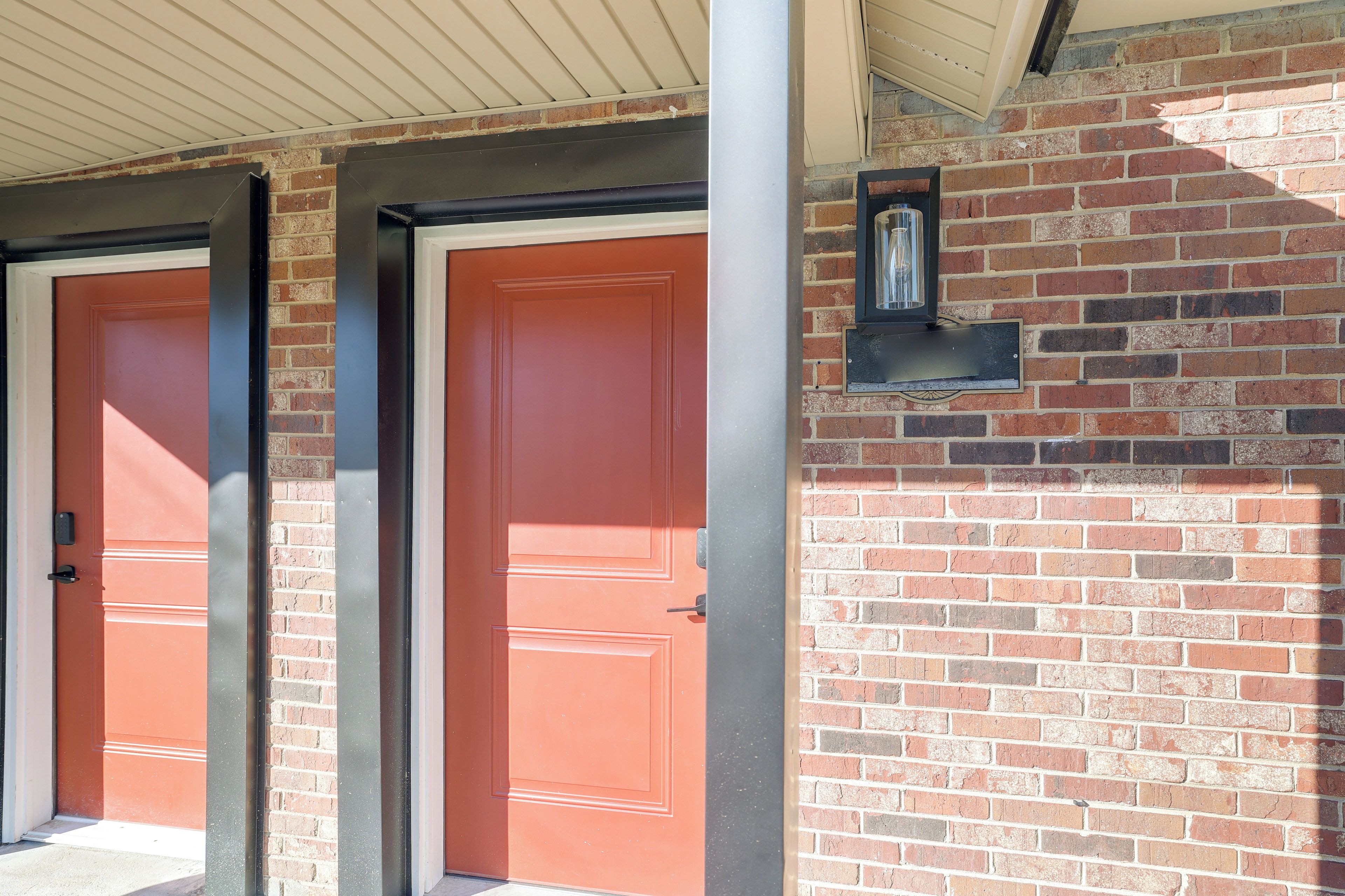 A building with two doors, a brick wall, and a small light fixture.