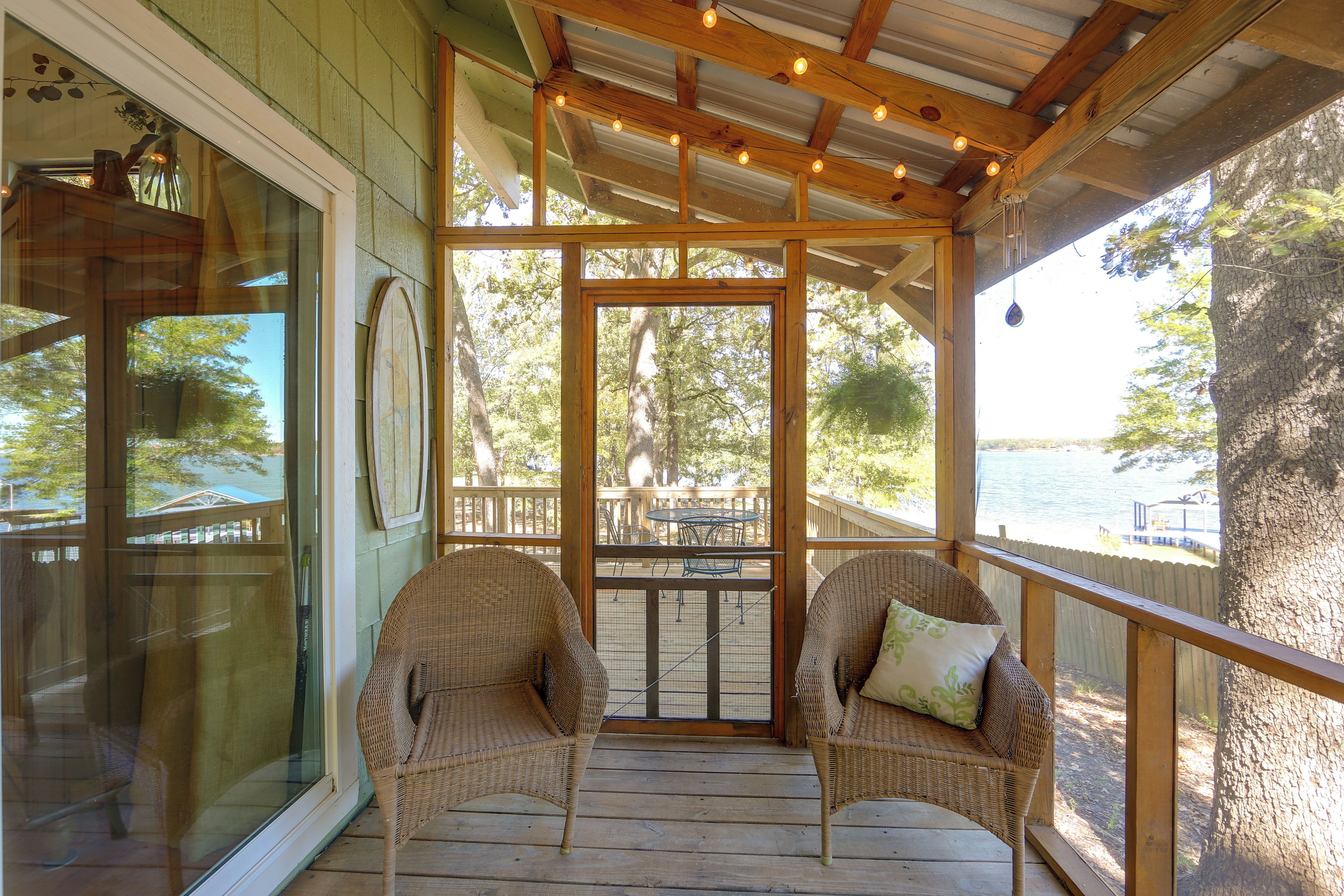 A covered porch with wicker chairs and a view of the outdoors.