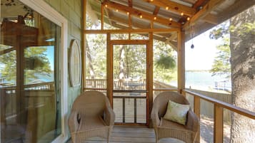 A covered porch with wicker chairs and a view of the outdoors.
