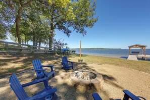 A lakeside outdoor seating area with Adirondack chairs, a fire pit, and a wooden deck overlooking the water. - Fishing Cabin on Lake Bob Sandlin (Leesburg)