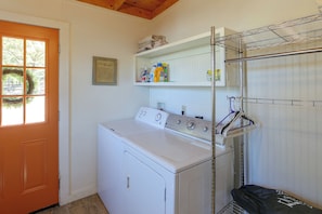 A laundry room with a front-loading washer and dryer, a drying rack, and shelves with cleaning supplies. - Fishing Cabin on Lake Bob Sandlin (Leesburg)
