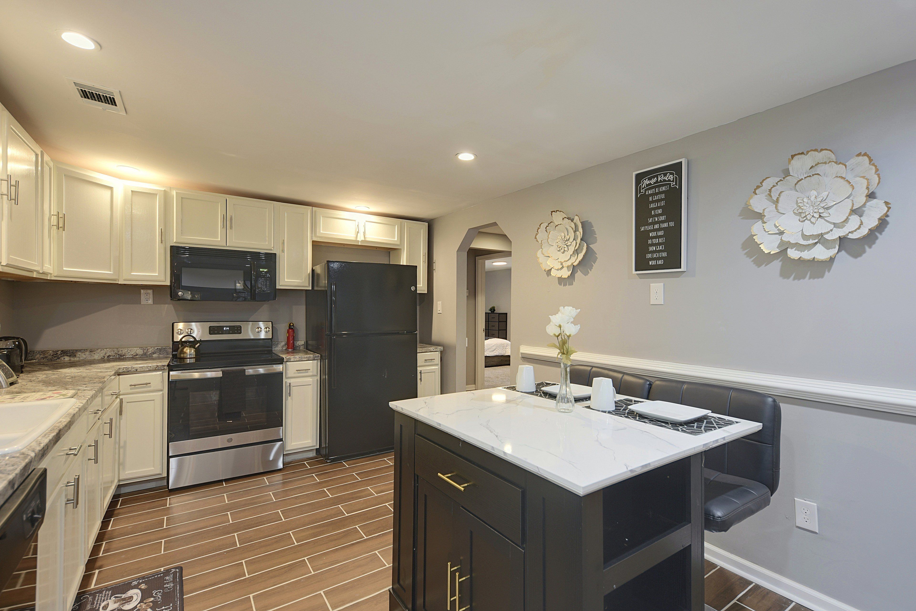 A modern kitchen with white cabinets, stainless steel appliances, and a marble countertop.