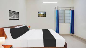 A bedroom with a bed, a nightstand, a lamp, a framed picture of a tiger, a framed landscape picture, and a window with curtains.