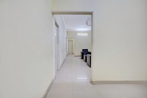 A hallway with a ceiling fan, a door at the end, and a seating area with chairs.