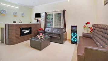 A modern living room with a sofa, a coffee table, a TV, and a speaker system.