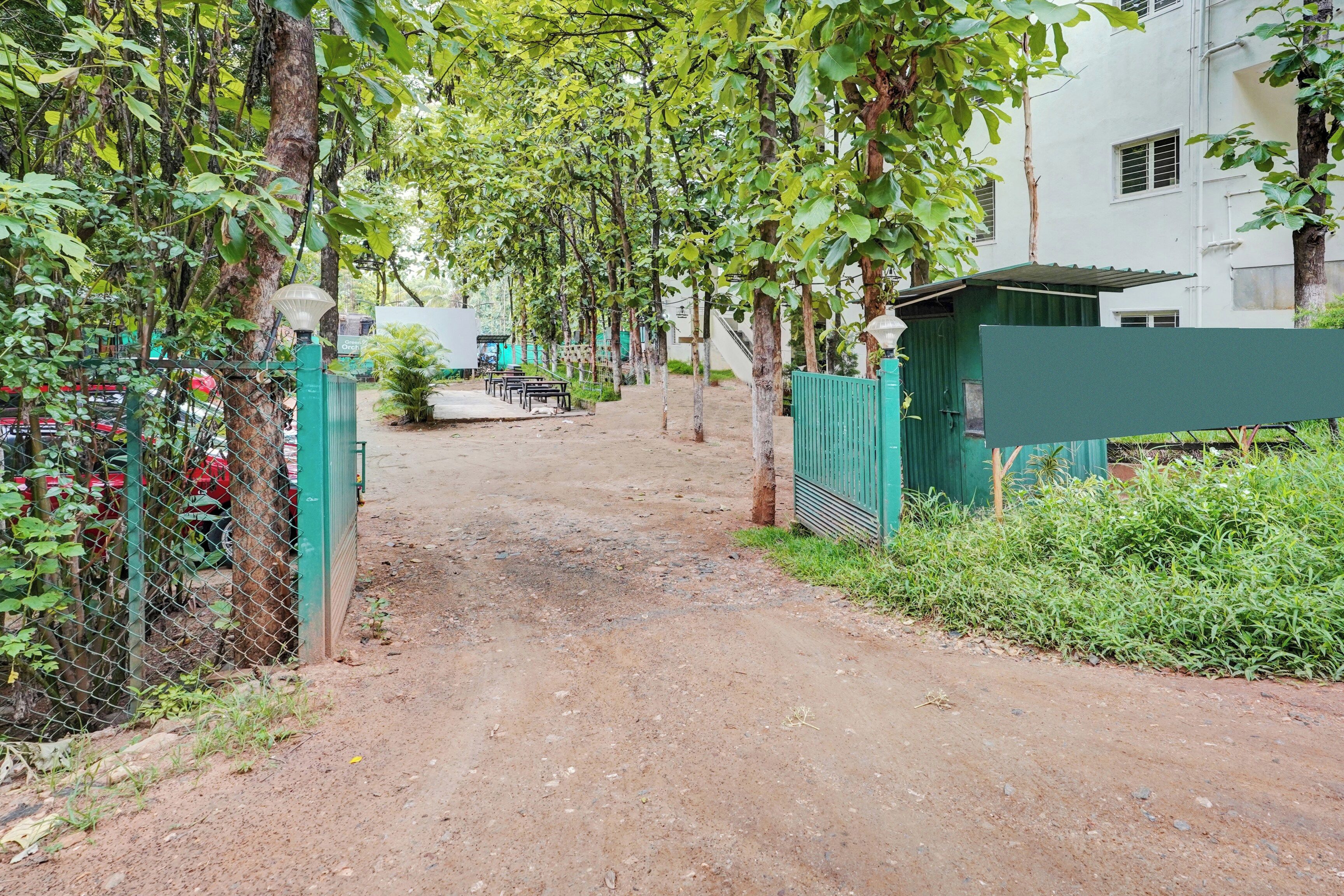 A dirt path leading to a gated area with a building in the background.