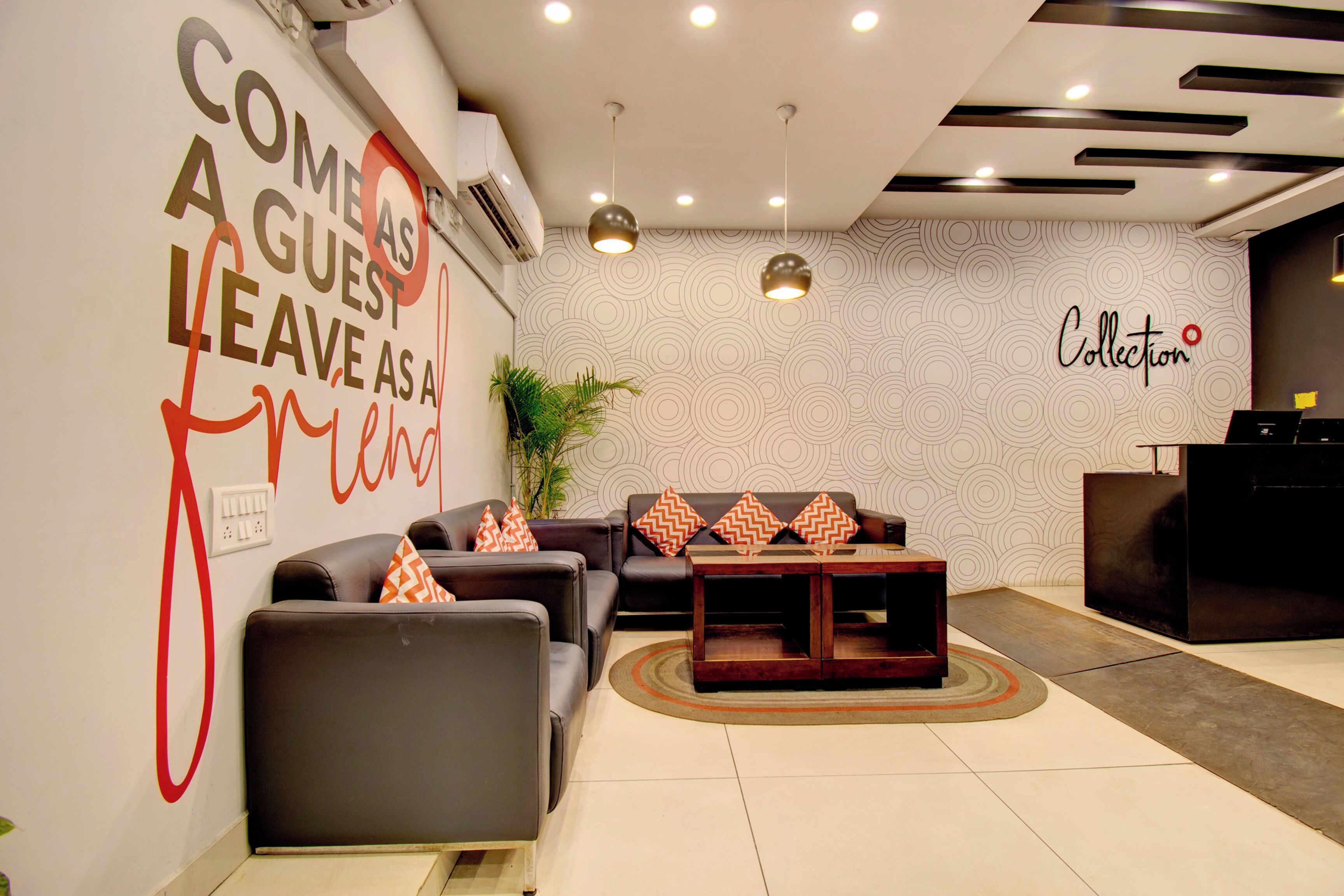 A modern lobby with a seating area, a reception desk, and a wall with a circular pattern.
