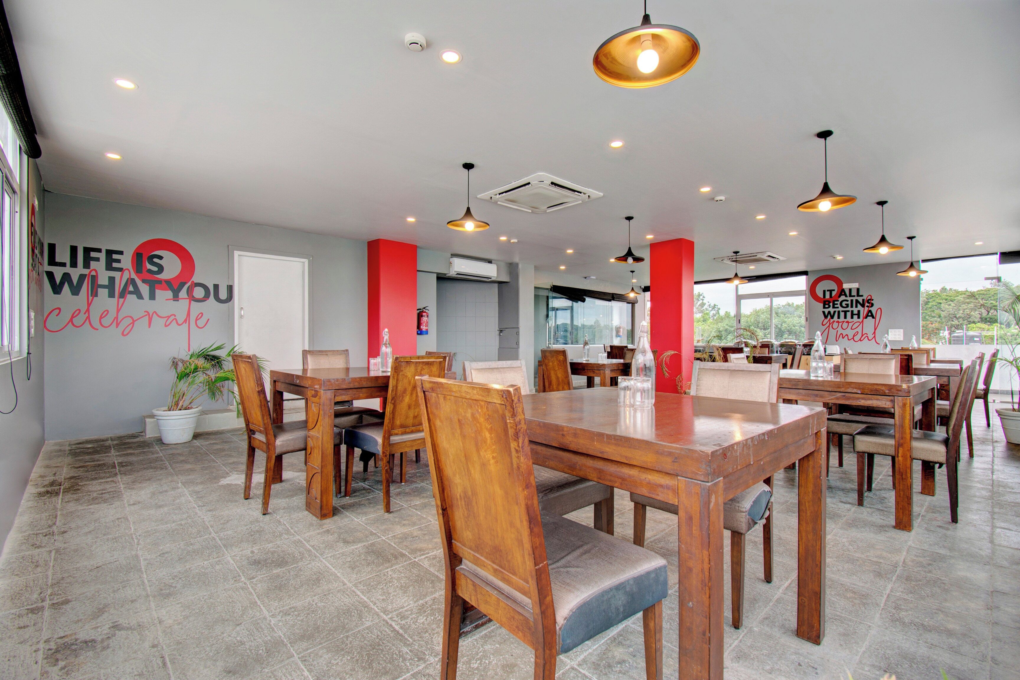Un comedor amplio con mesas y sillas de madera, una pizarra con citas motivacionales y vistas a través de grandes ventanales.