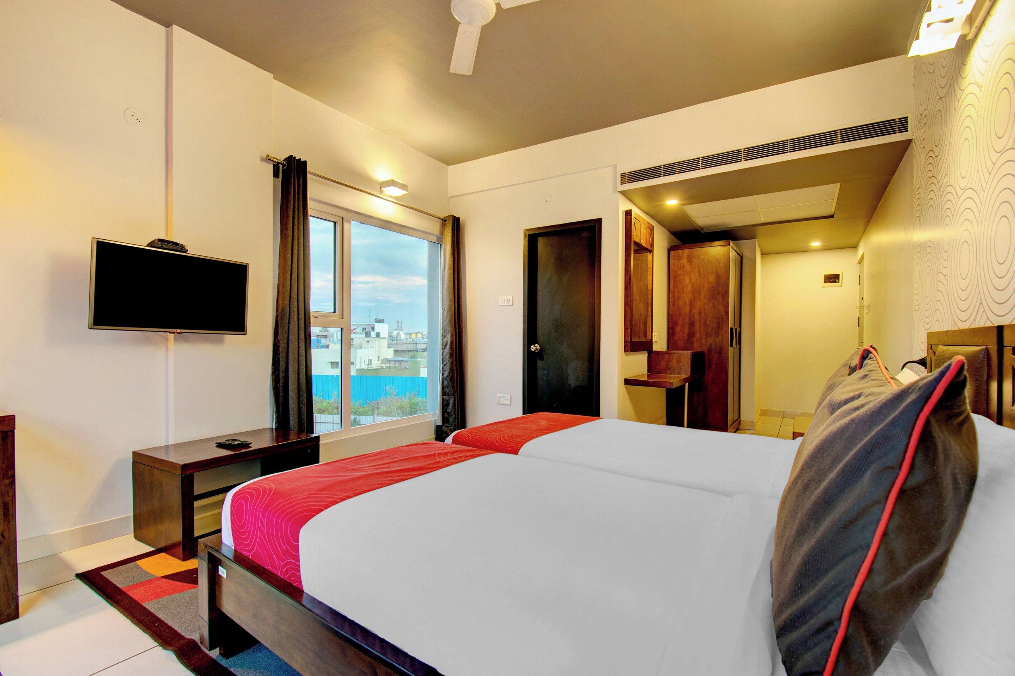 Habitación de hotel con cama, televisor, escritorio y ventana con vistas.