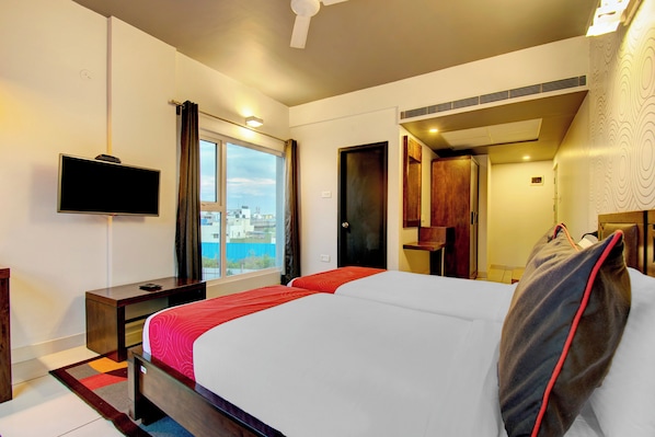 Habitación de hotel con cama, televisor, escritorio y ventana con vistas.