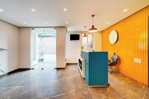 Un interior moderno con una recepción, un espejo grande y un área de estar.