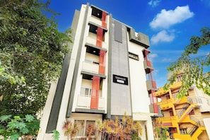 Un edificio de varios pisos con balcones, un letrero que indica que es una casa townhouse con servicios de empresa, y follaje circundante.