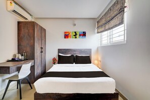 Un dormitorio con cama, escritorio y armario. Hay tres cuadros en la pared.